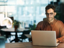 An employee sitting at a table with their laptop.