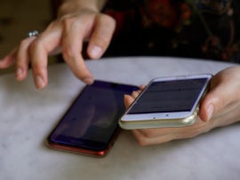 Woman navigating two iphones at the same time.